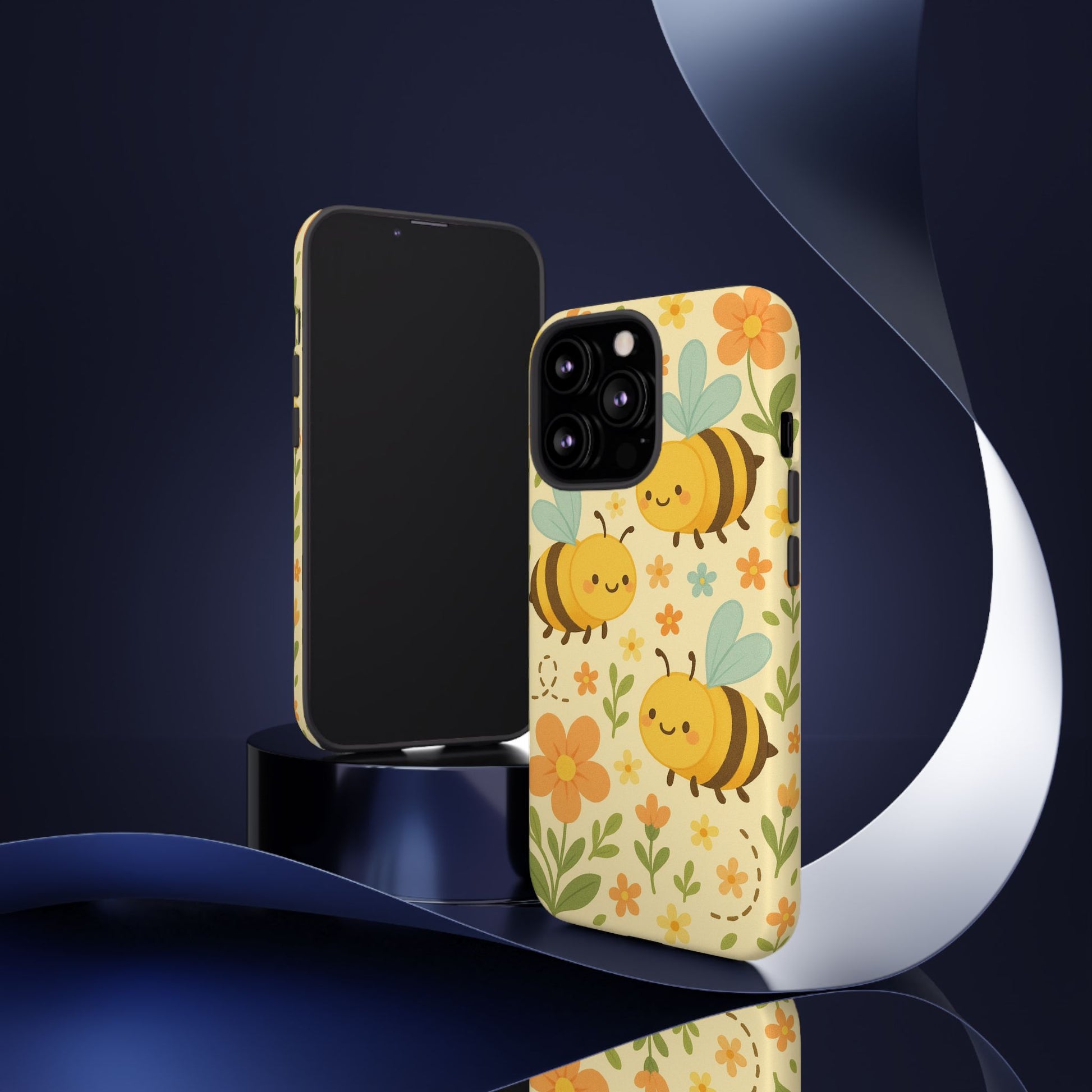 Two smartphones are shown: one with a blank screen, the other with the Printify Cute Cartoon Floral Bee Tough Phone Case, featuring cheerful bees and flowers—an ideal gift for bee lovers—set against a dark background with metallic accents.