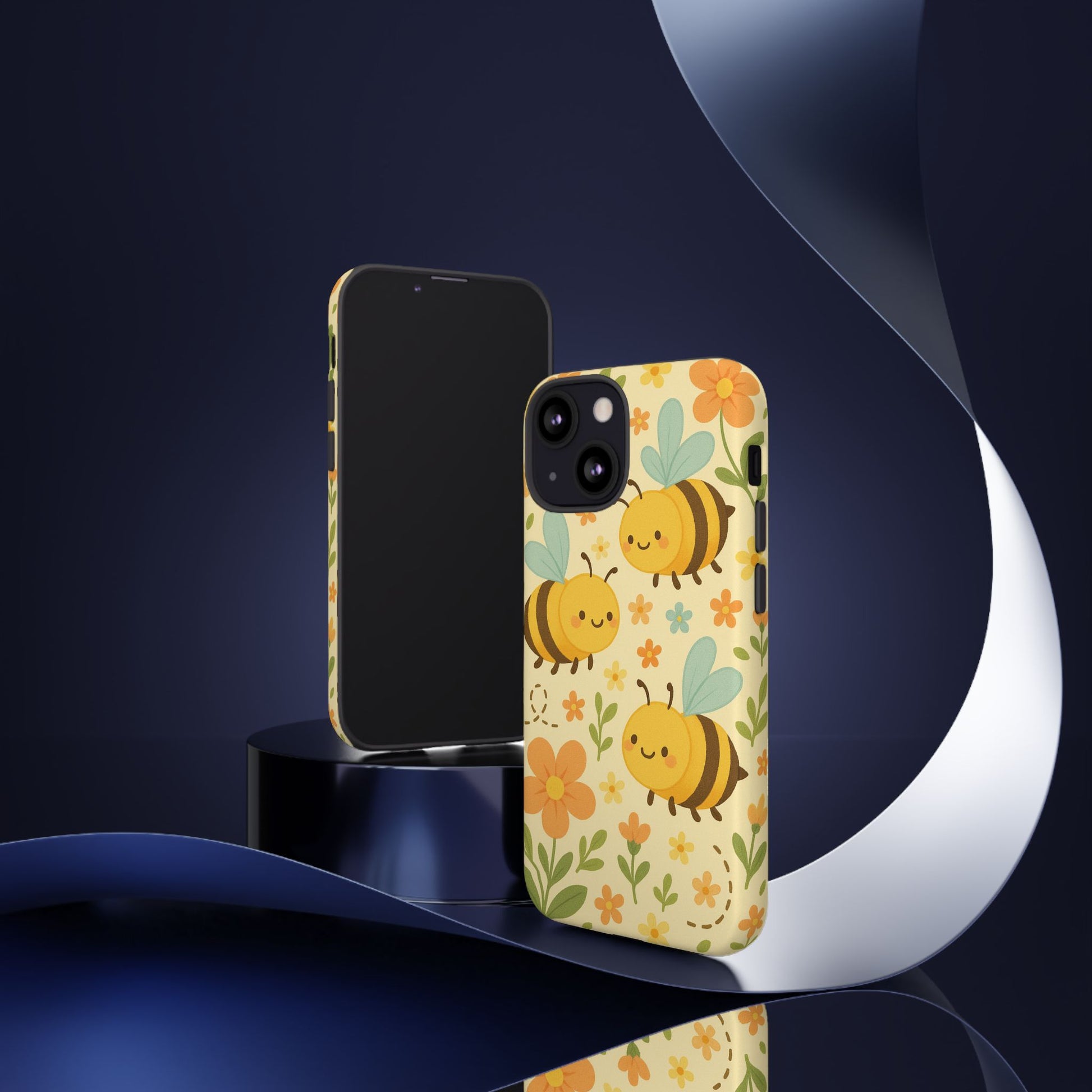 Two smartphones with Printify’s Cute Cartoon Floral Bee Tough Phone Case in yellow are displayed on a glossy platform, accented by a blue metallic ribbon—a modern, stylish touch and a perfect gift for bee lovers.