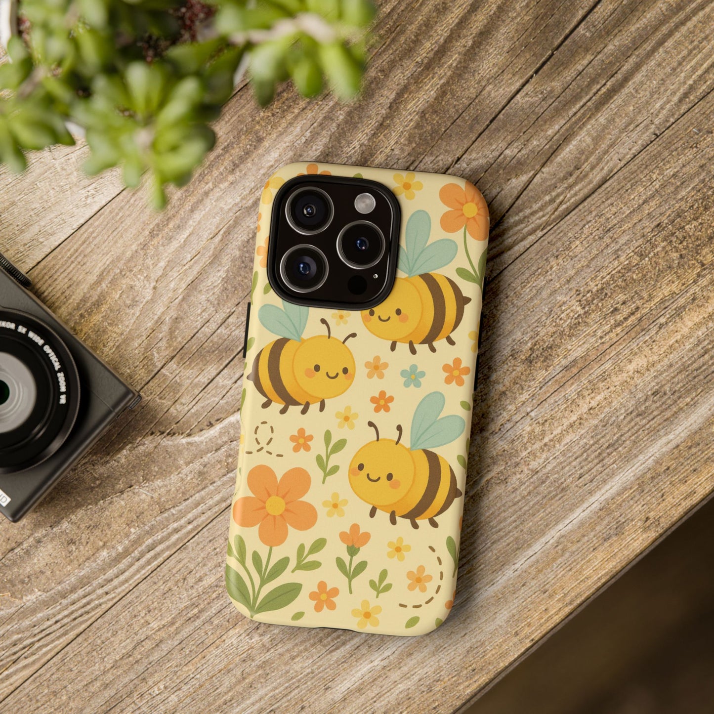 Phone case with bee and flower design on a wooden surface