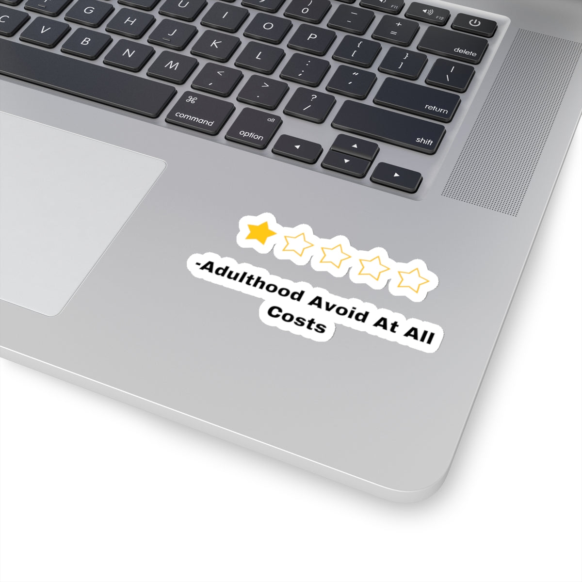 Printify adulthood review sticker with one yellow star and quote on silver laptop near keyboard