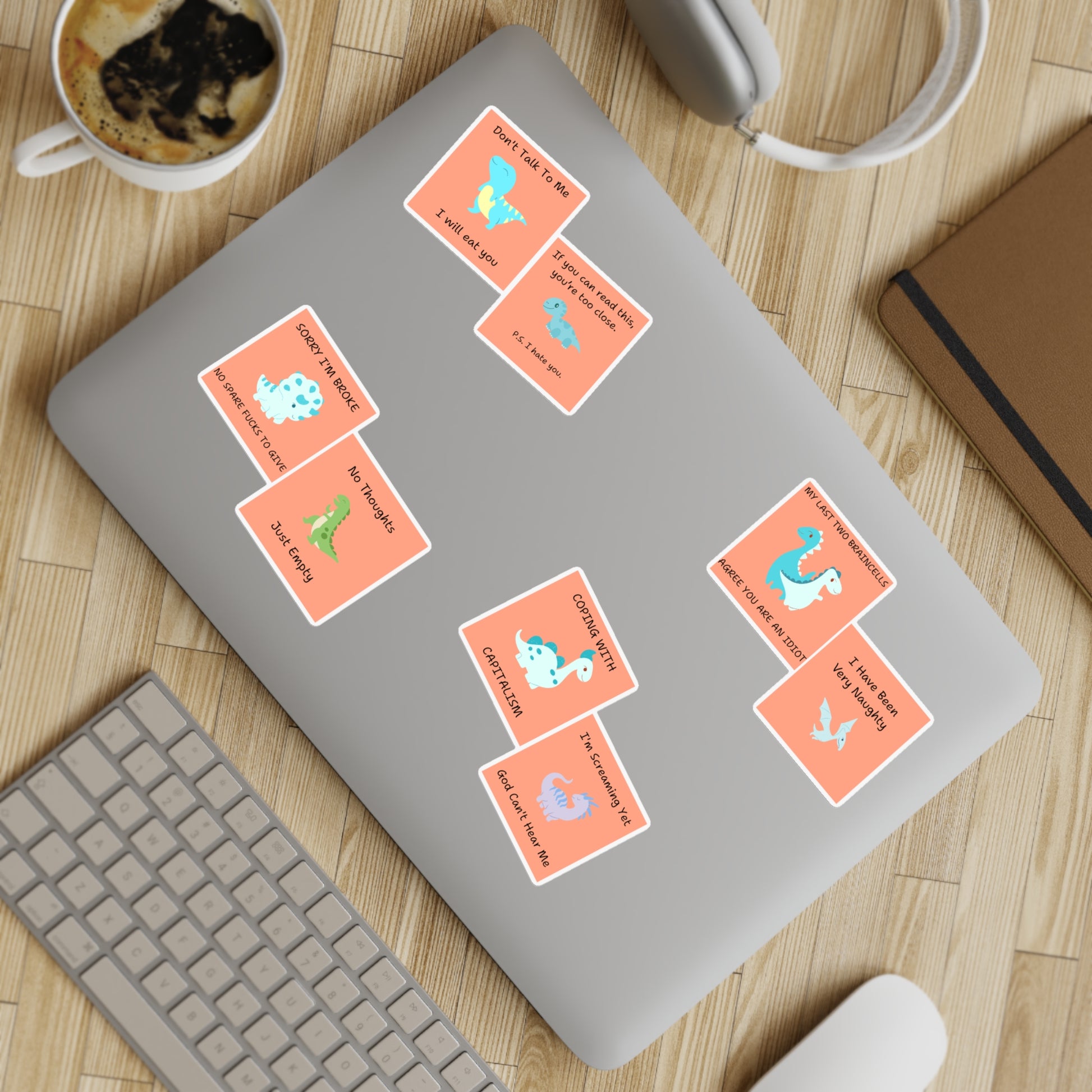 Funny edgy sarcastic cute dino sticker bundle displayed on a laptop with coffee and keyboard