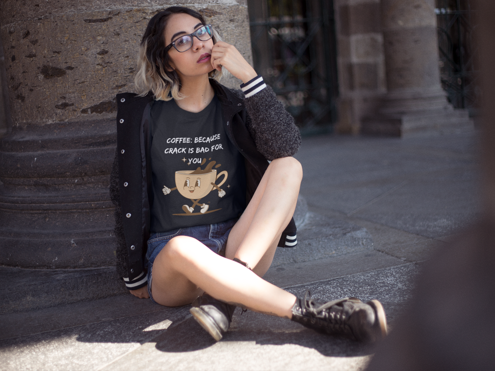 Young woman sitting outdoors wearing black Printify T Shirt with coffee cup graphic and coffee because crack is bad for you shirt