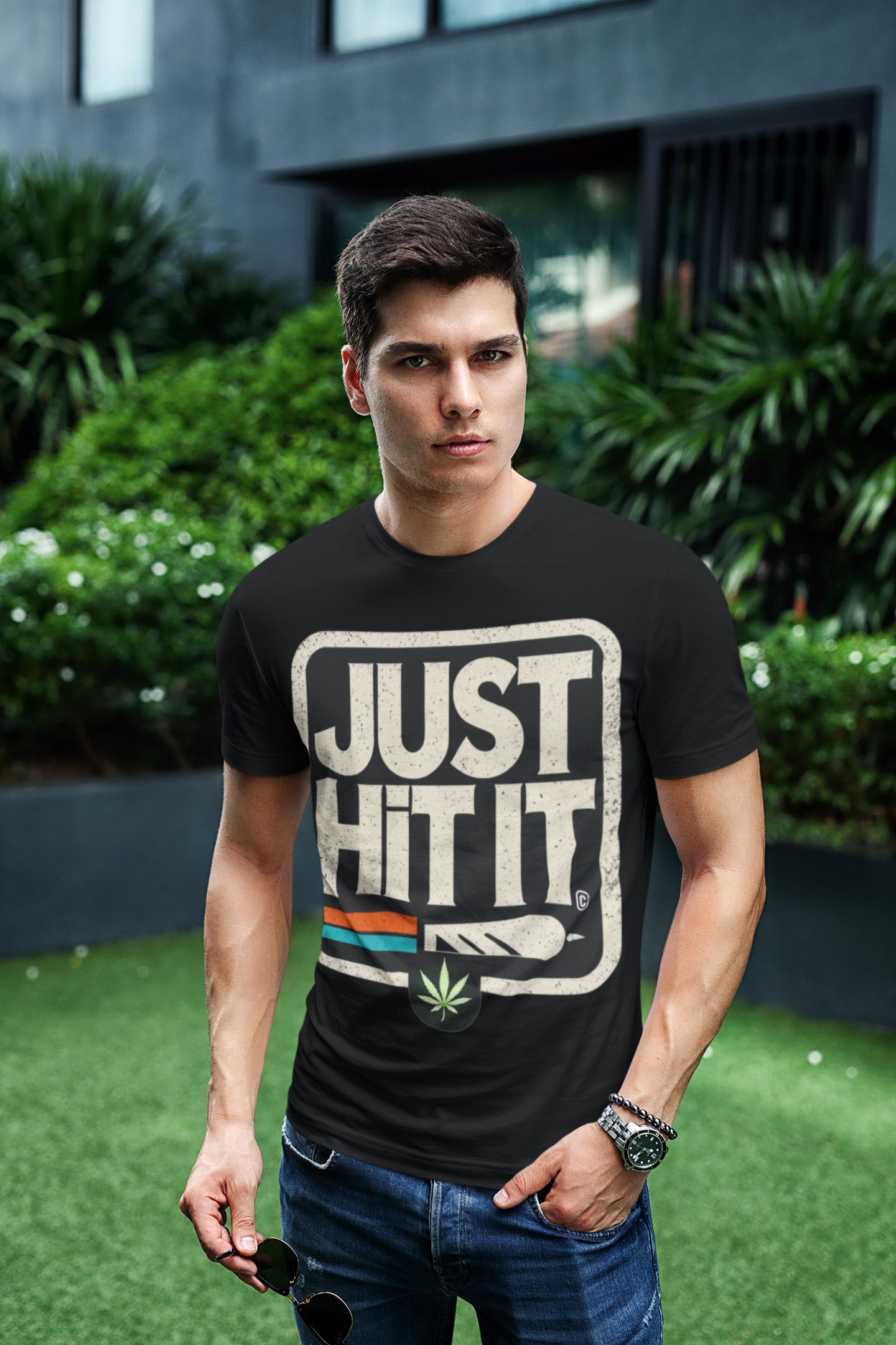 Male model wearing Printify black funny weed just do it meme  t-shirt with JUST HIT IT weed leaf graphic outdoors