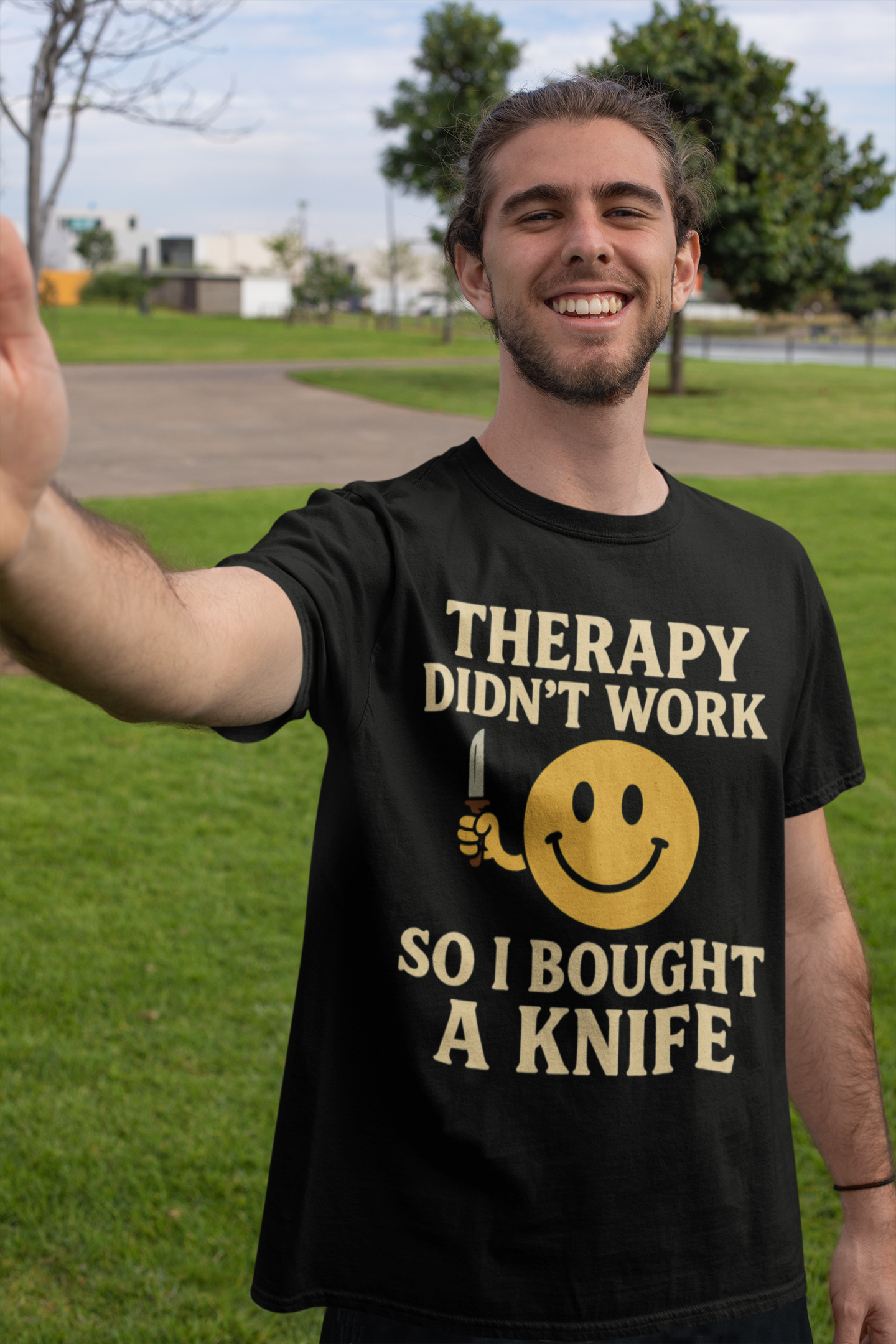 Smiling man outdoors wearing black shirt with yellow smiley holding knife and text therapy dark joke humor unisex  t shirt .