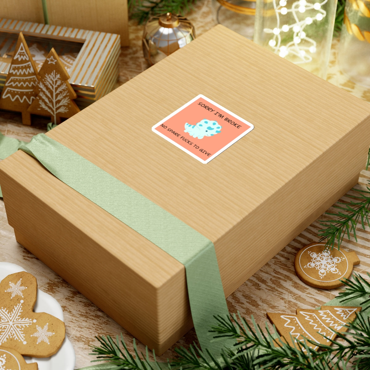 Gift box with no fucks to give funny dino sticker on top surrounded by holiday decorations