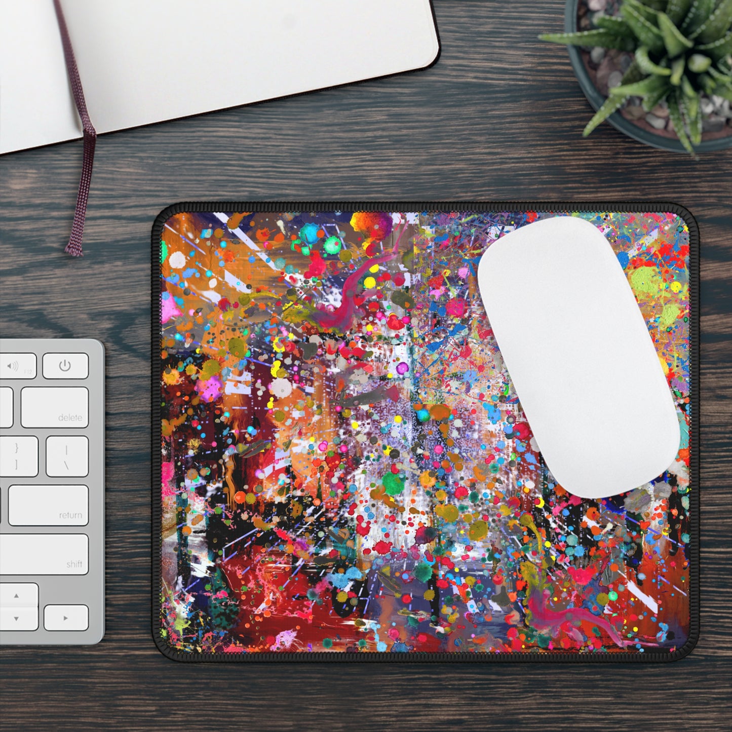 Urban chaos abstract neon splatter art mousepad on a wooden desk beside a keyboard and plant