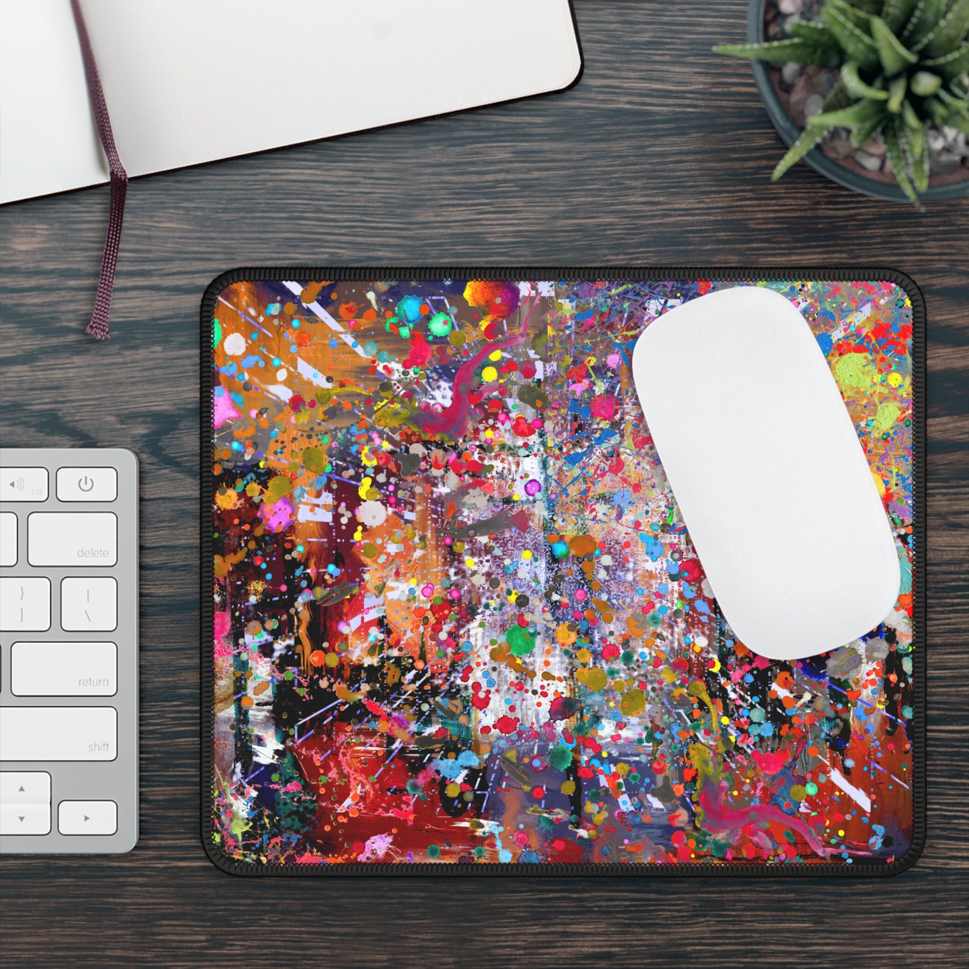 Urban chaos abstract neon splatter art mousepad on a wooden desk beside a keyboard and plant
