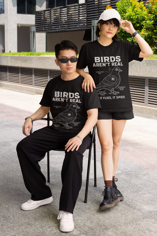 Printify black T shirt photo of two models wearing birds aren't real meme shirt with schematic bird graphic and slogan