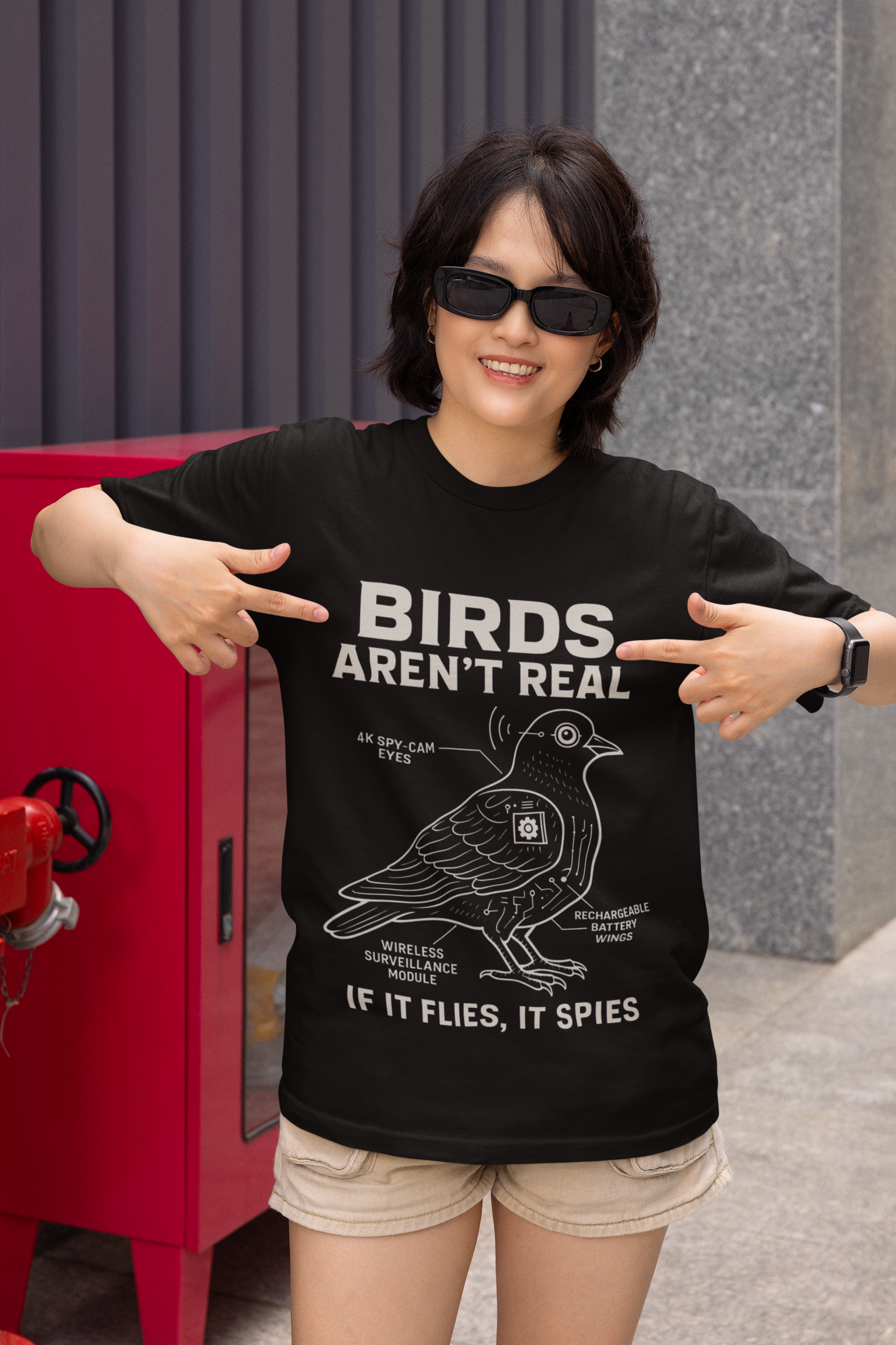 Woman wearing a black birds aren't real meme shirt showing white schematic bird graphic