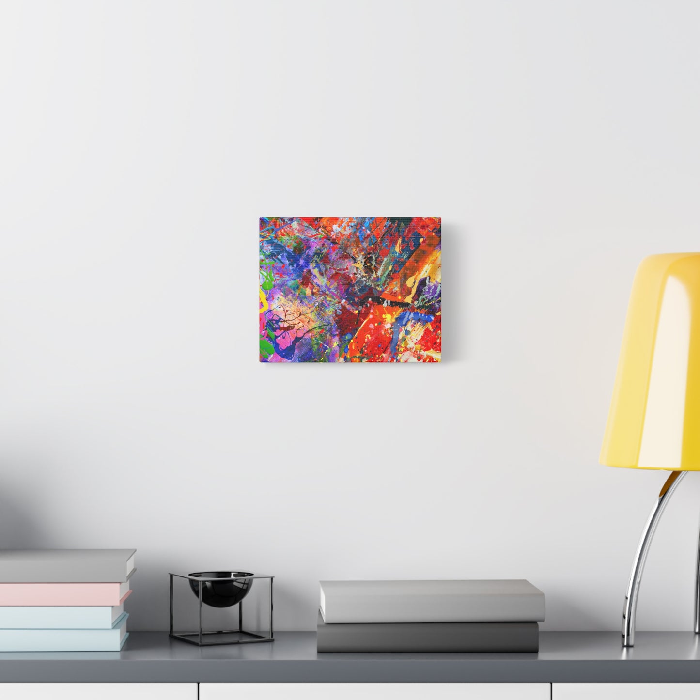 Colorful canvas abstract art print kaleidoscope collision hanging on white wall above modern desk